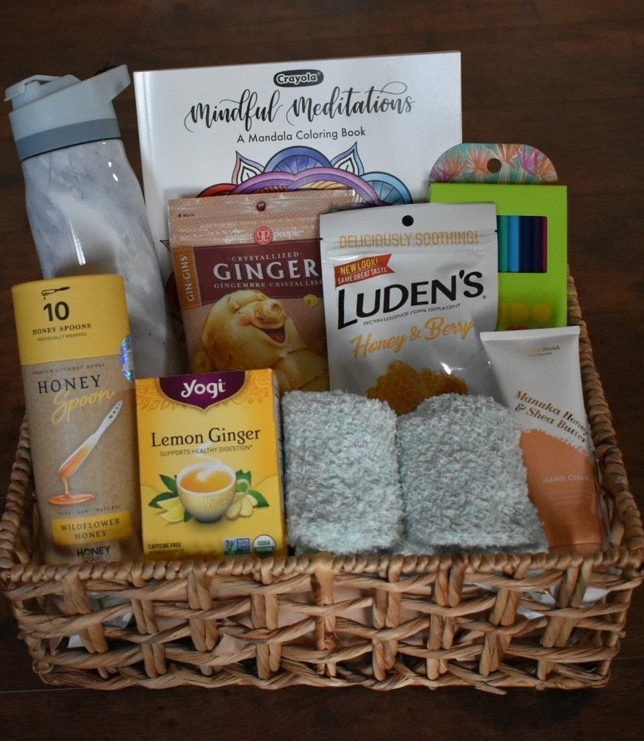 Woven gift basket containing tea, honey, candy, socks, and a coloring book.