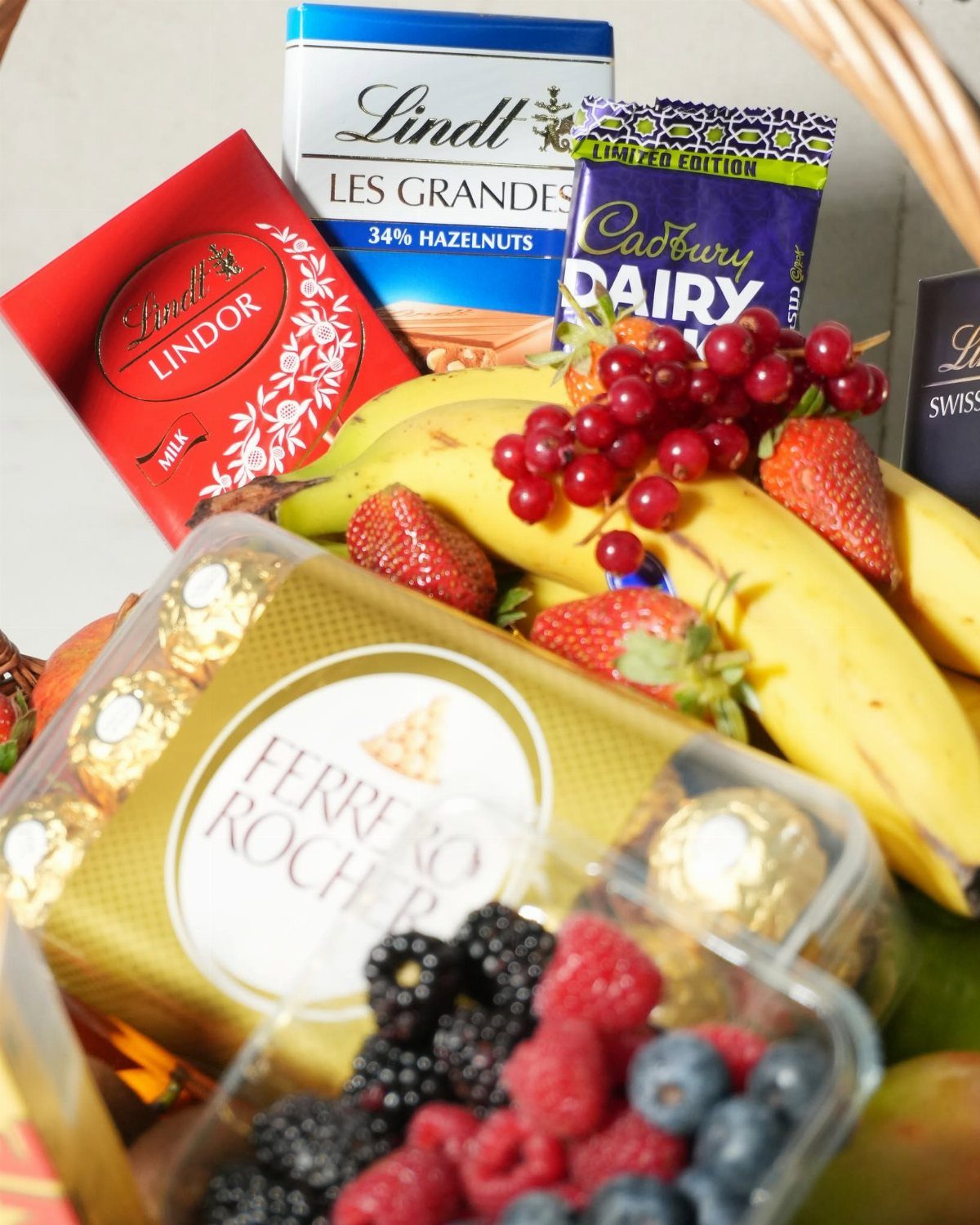 Gift basket filled with assorted chocolates and fresh berries and bananas