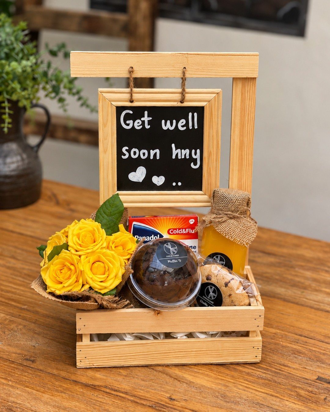 Get well care package in a wooden crate with roses, honey, and medicine.