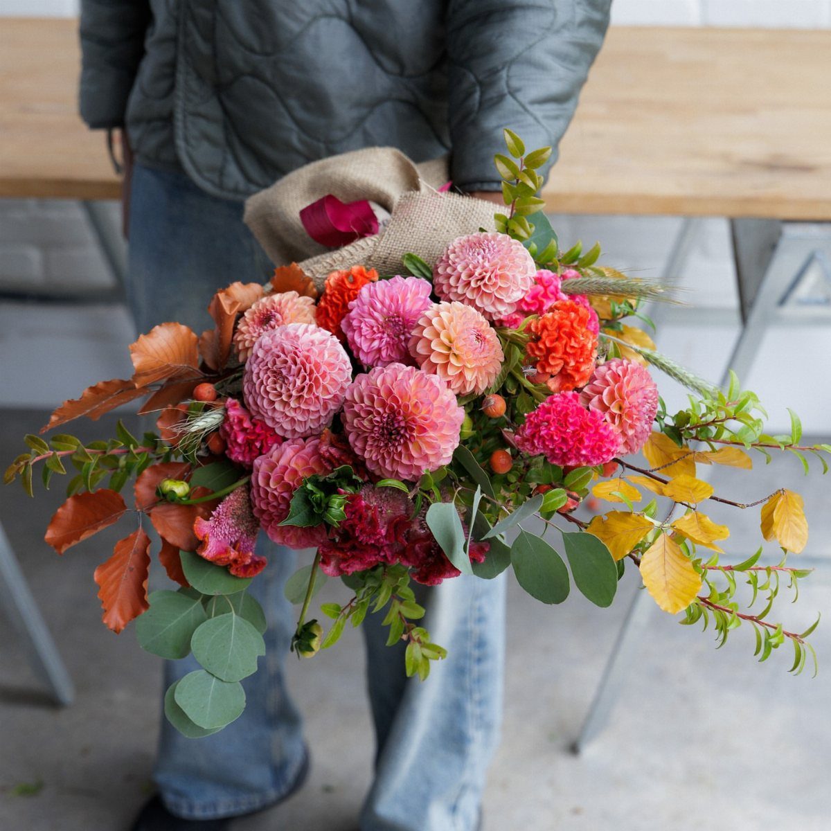 Large bouquet of pink and orange dahlias with eucalyptus leaves held by person