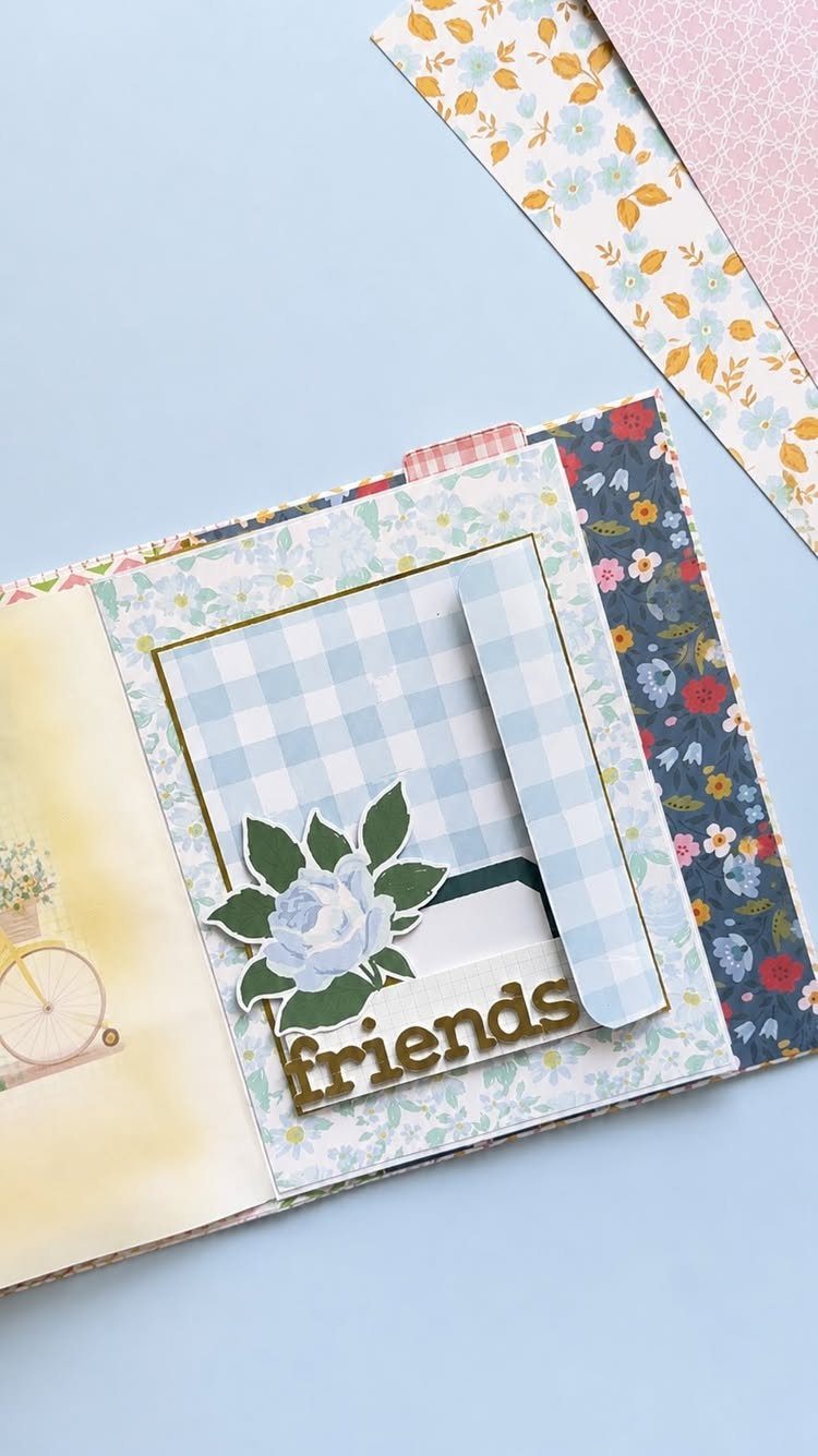 Open scrapbook page with floral patterns, a checkered photo slot, and gold friends text.