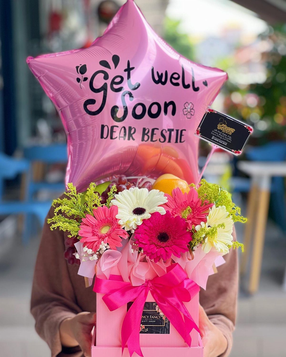 Pink gift box with colorful flowers and a star-shaped get well soon balloon.