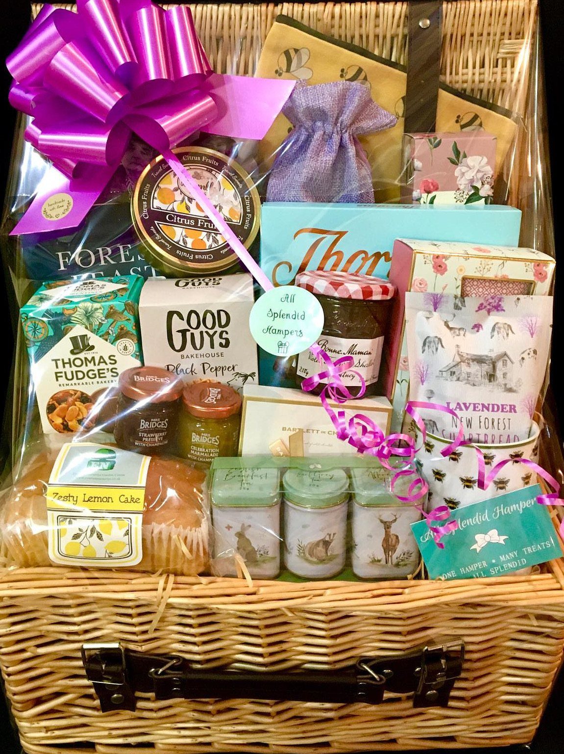 Wicker gift basket filled with gourmet snacks and treats wrapped in clear cellophane.