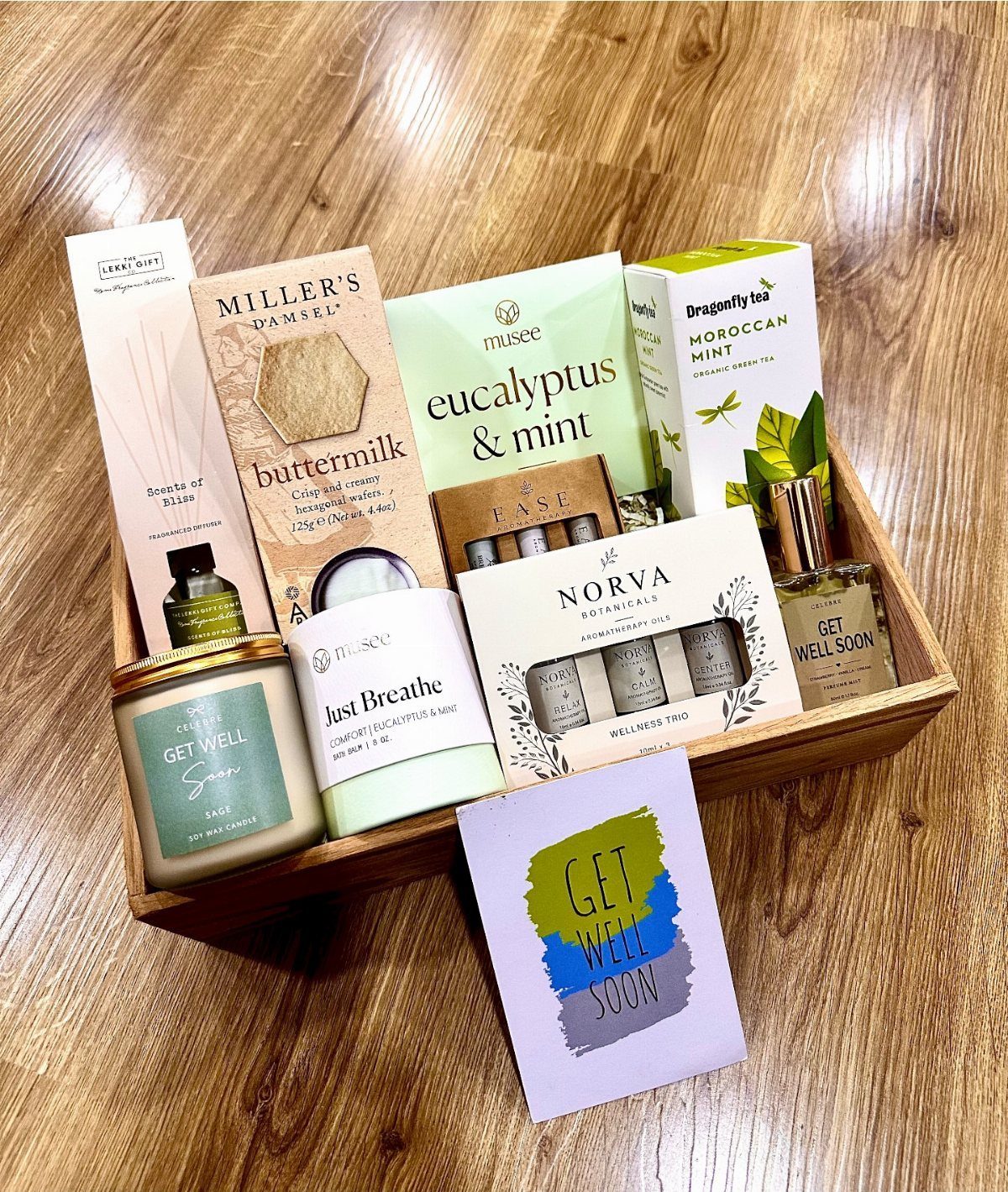 Wellness gift basket with tea, candles, and a get well soon card in a tray.