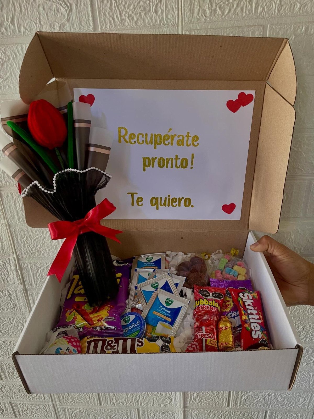 Care package box with candies, a red flower bouquet, and a get well card.