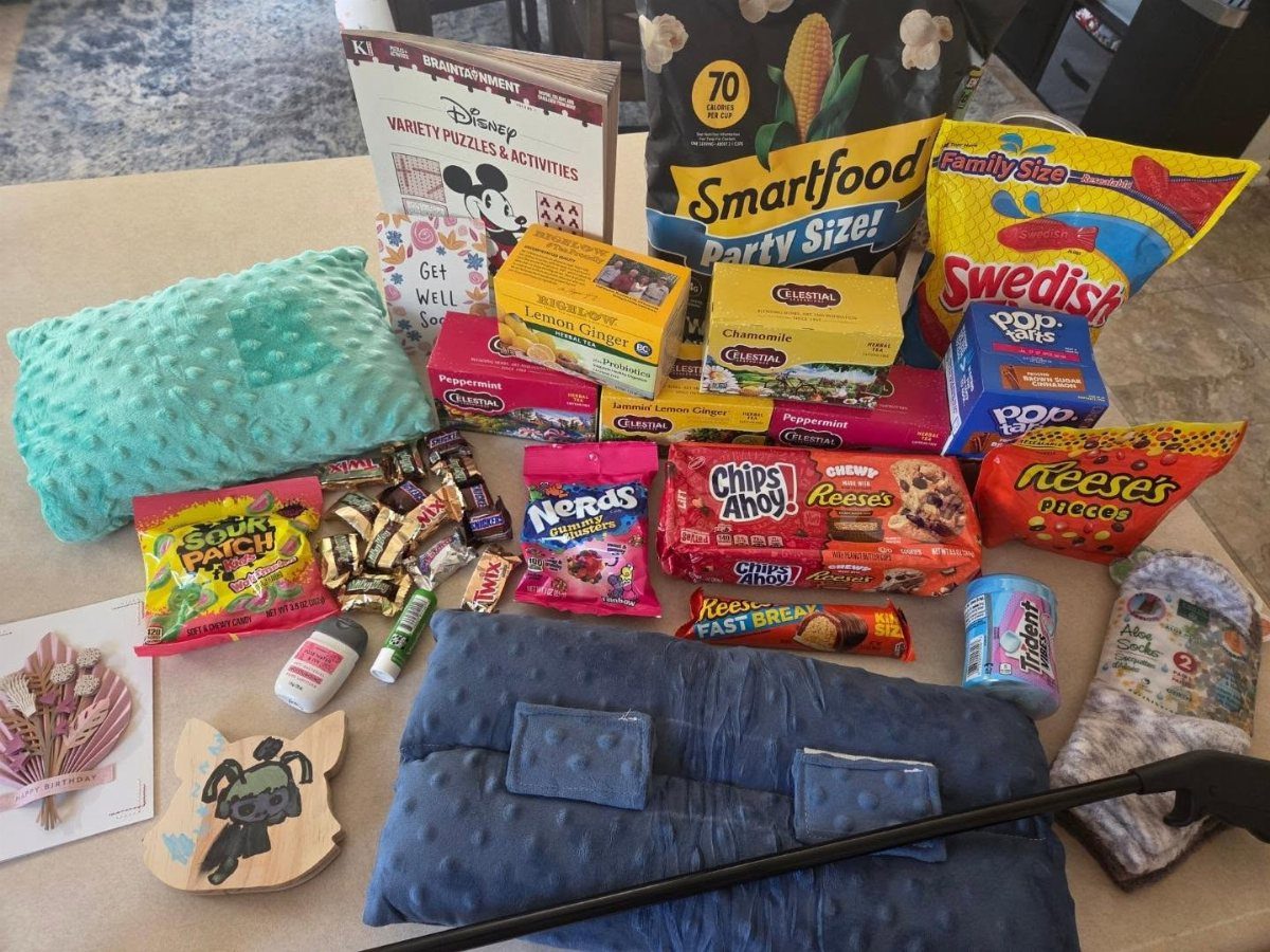 Care package with snacks, pillows, and a puzzle book on a table.