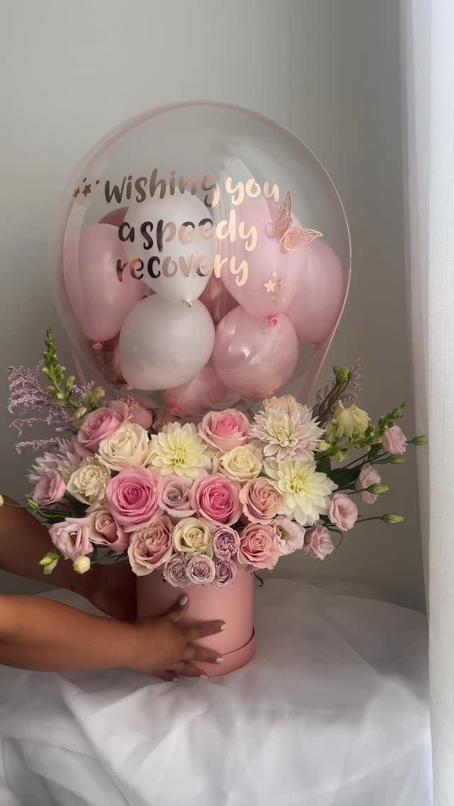 Get well gift featuring a flower arrangement and a recovery message balloon.