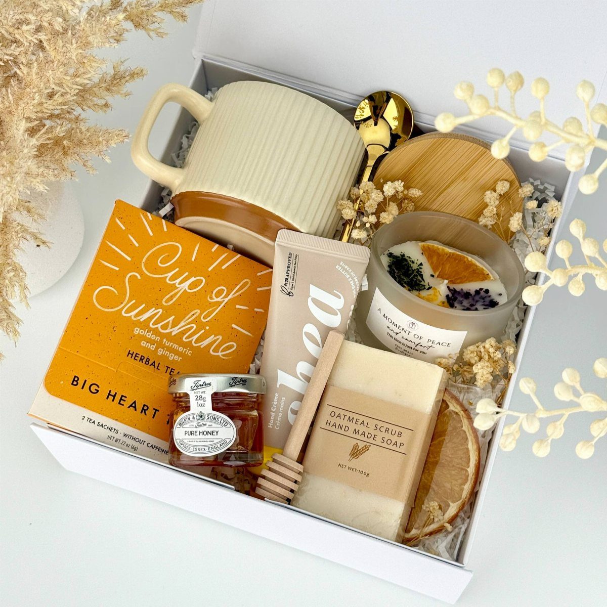 Curated gift box containing a mug, honey, herbal tea, soap, and a candle.