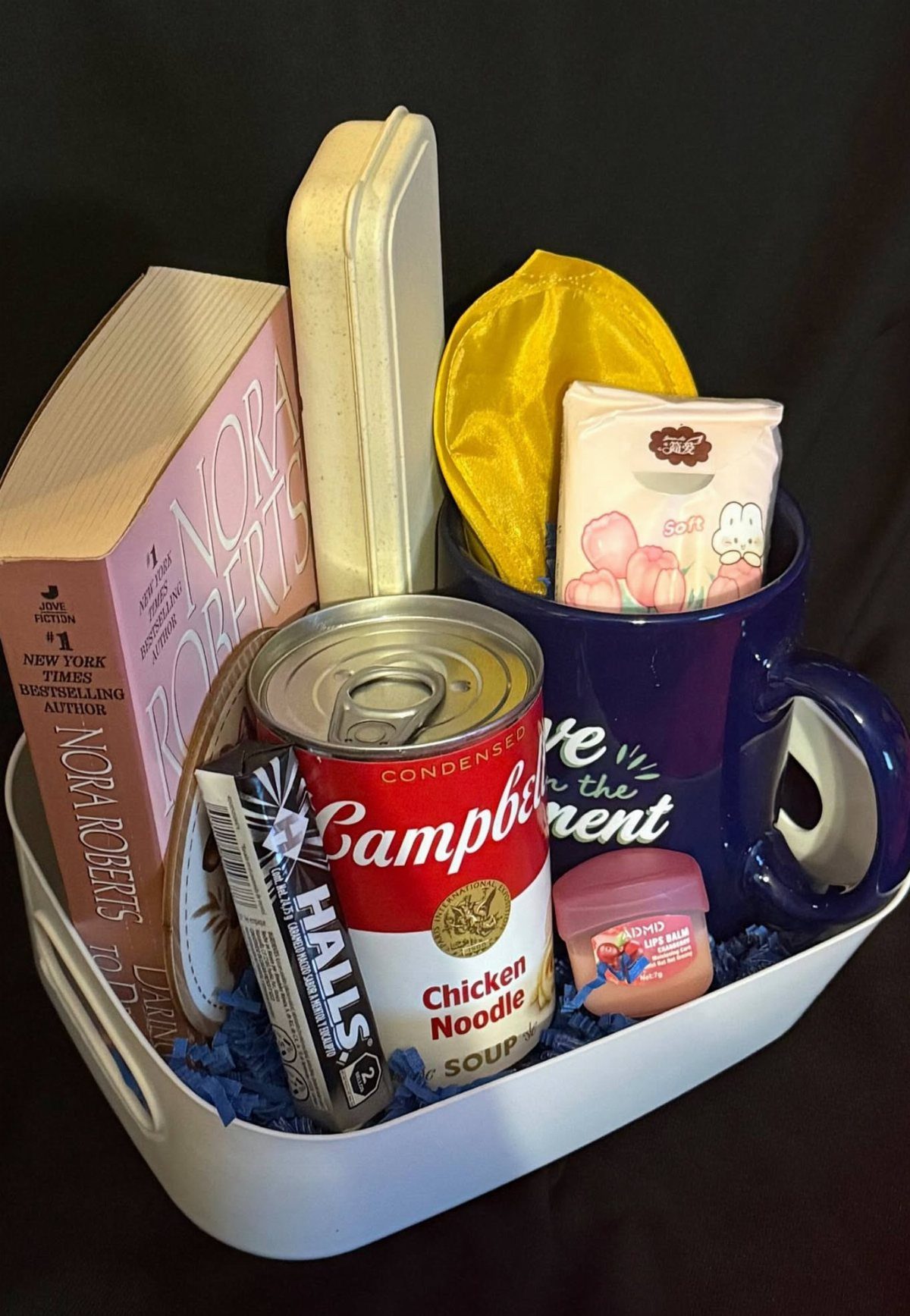 Get well kit in a white bin with soup, book, and cough drops.
