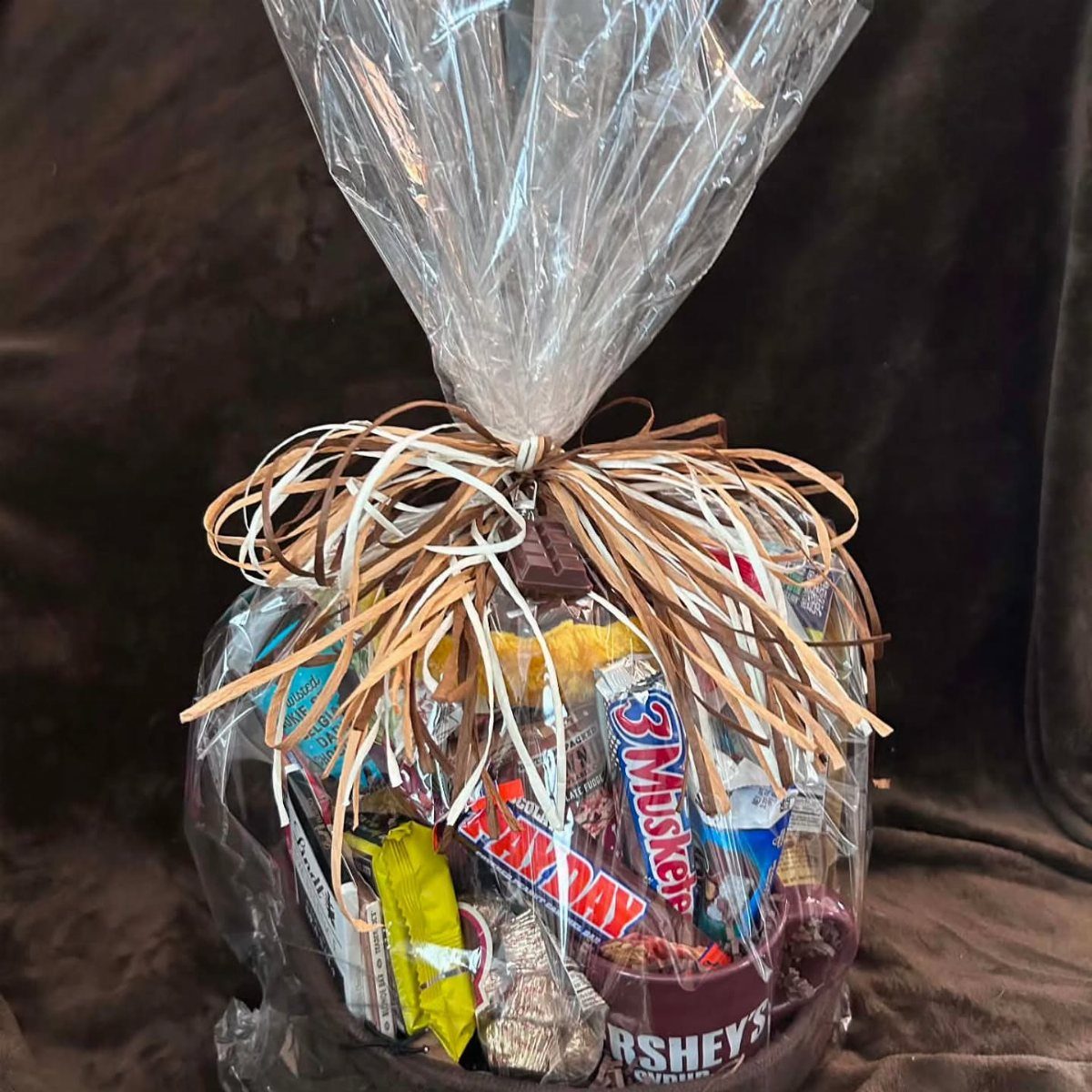 Chocolate candy gift basket wrapped in clear cellophane with a decorative bow.