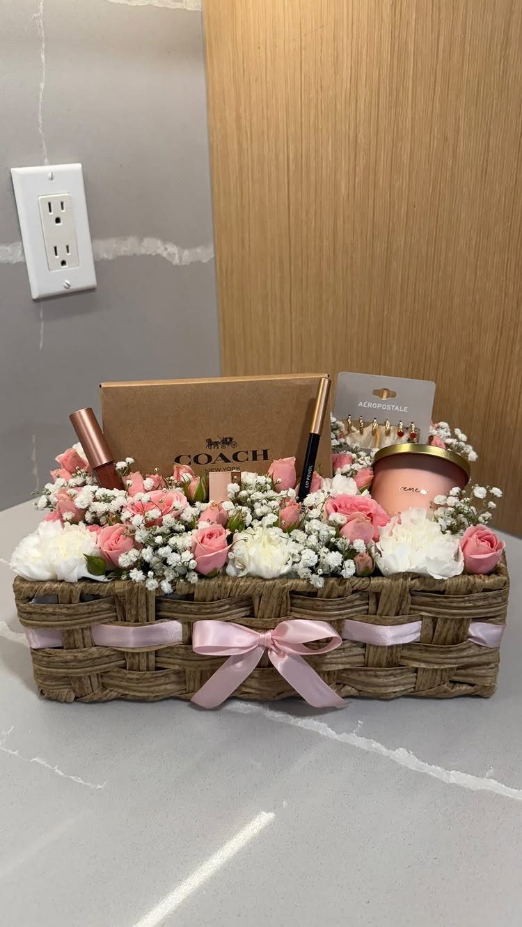 Woven gift basket with pink and white flowers, Coach wallet, and beauty products.