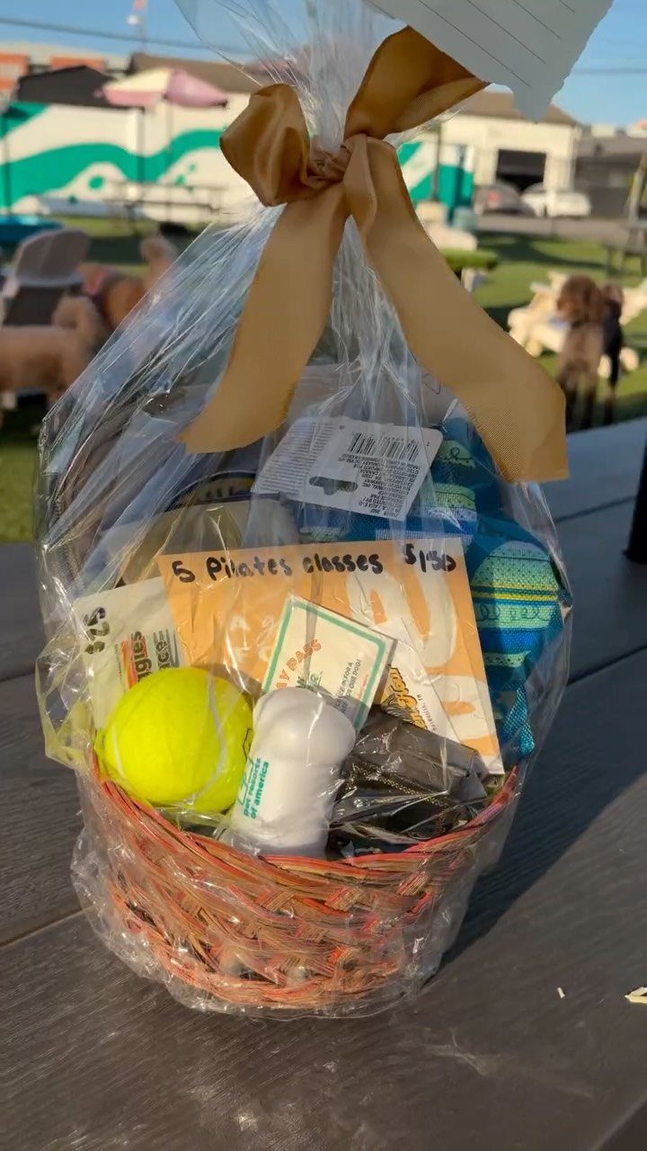 Wicker gift basket with tennis ball and Pilates classes certificate wrapped in cellophane.