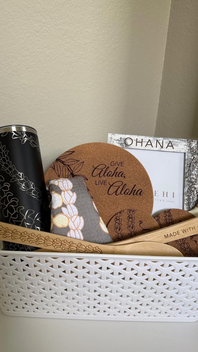 White lattice gift basket filled with Hawaiian themed items, tumbler, and wooden utensils.