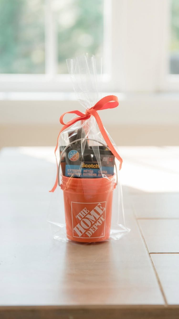 Orange Home Depot bucket gift basket wrapped in cellophane with a red ribbon.