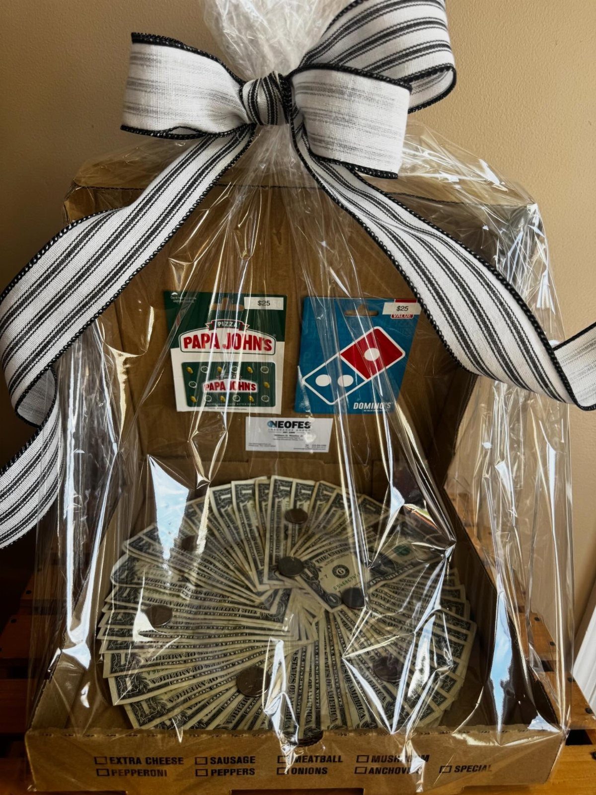 Pizza box gift basket containing pizza gift cards and a fan of cash.