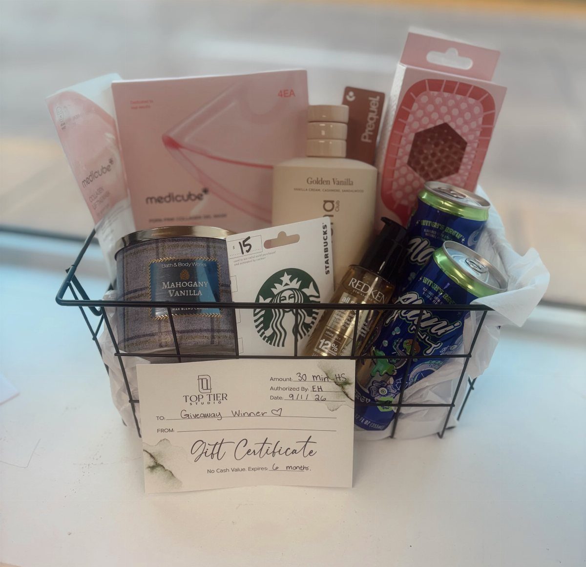Gift basket containing skincare products, a candle, lotion, and a Starbucks gift card.
