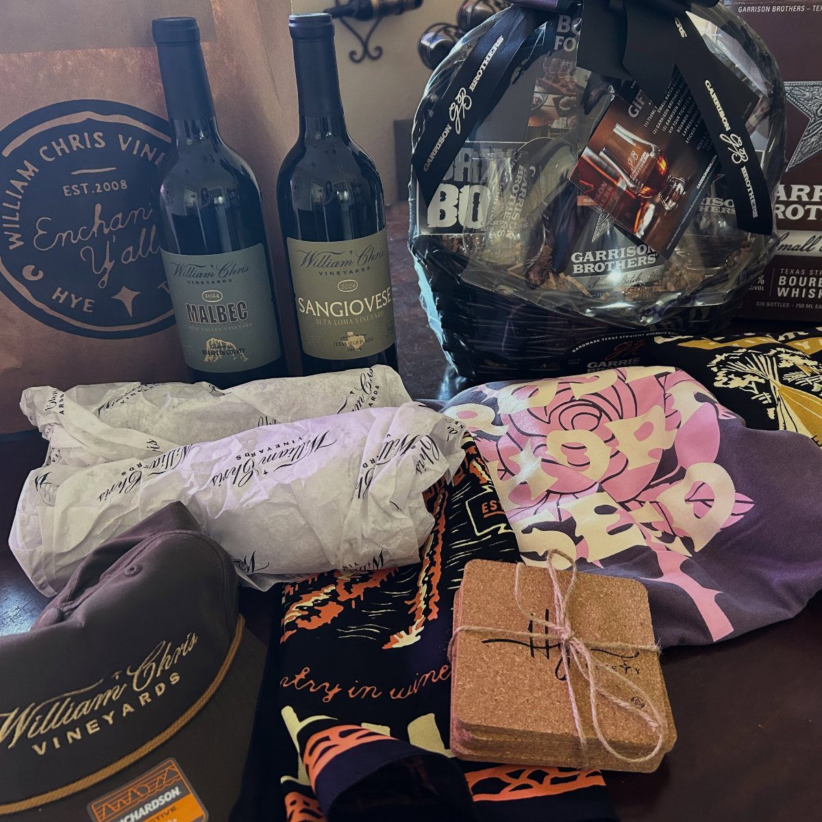 Two bottles of red wine and vineyard merchandise arranged as a gift set.