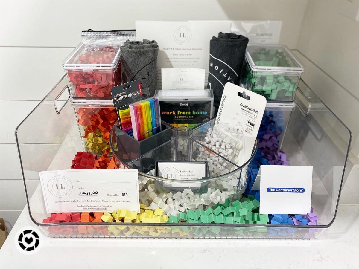 Clear plastic gift bin with colorful filler and work from home office supplies.