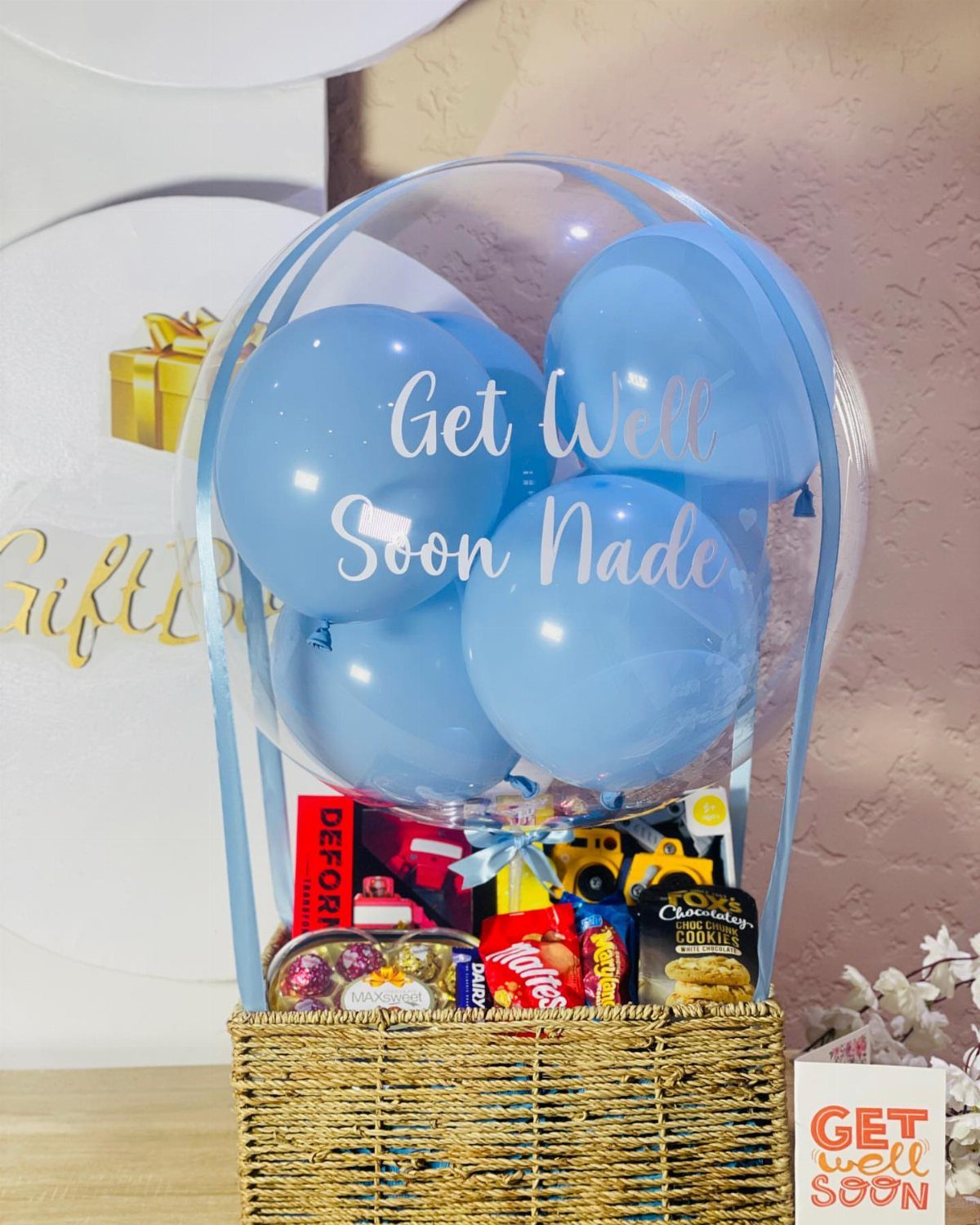 Woven gift basket with snacks and a blue balloon hot air balloon arrangement.