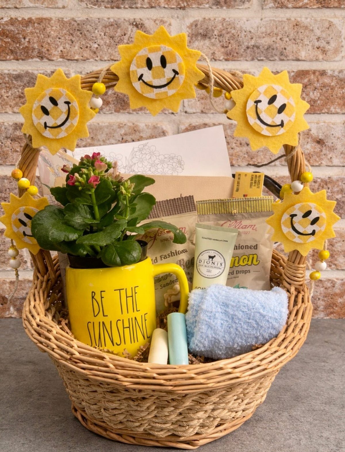 Wicker gift basket with yellow smiley face suns, a sunshine mug, and treats.