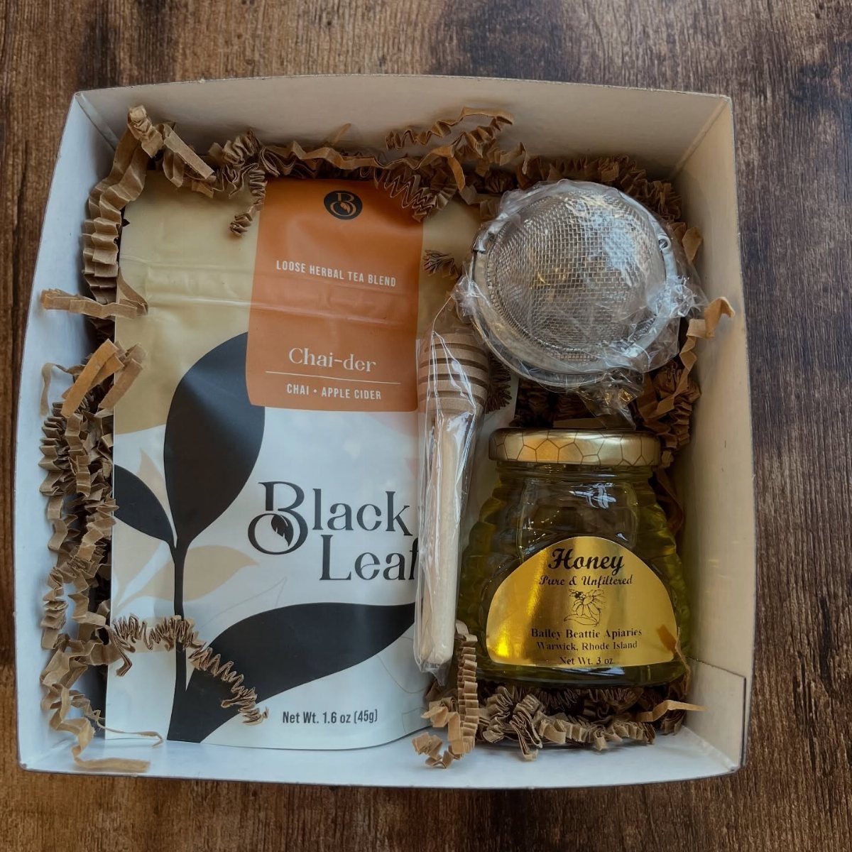 Tea and honey gift set in a white box with brown filler paper.