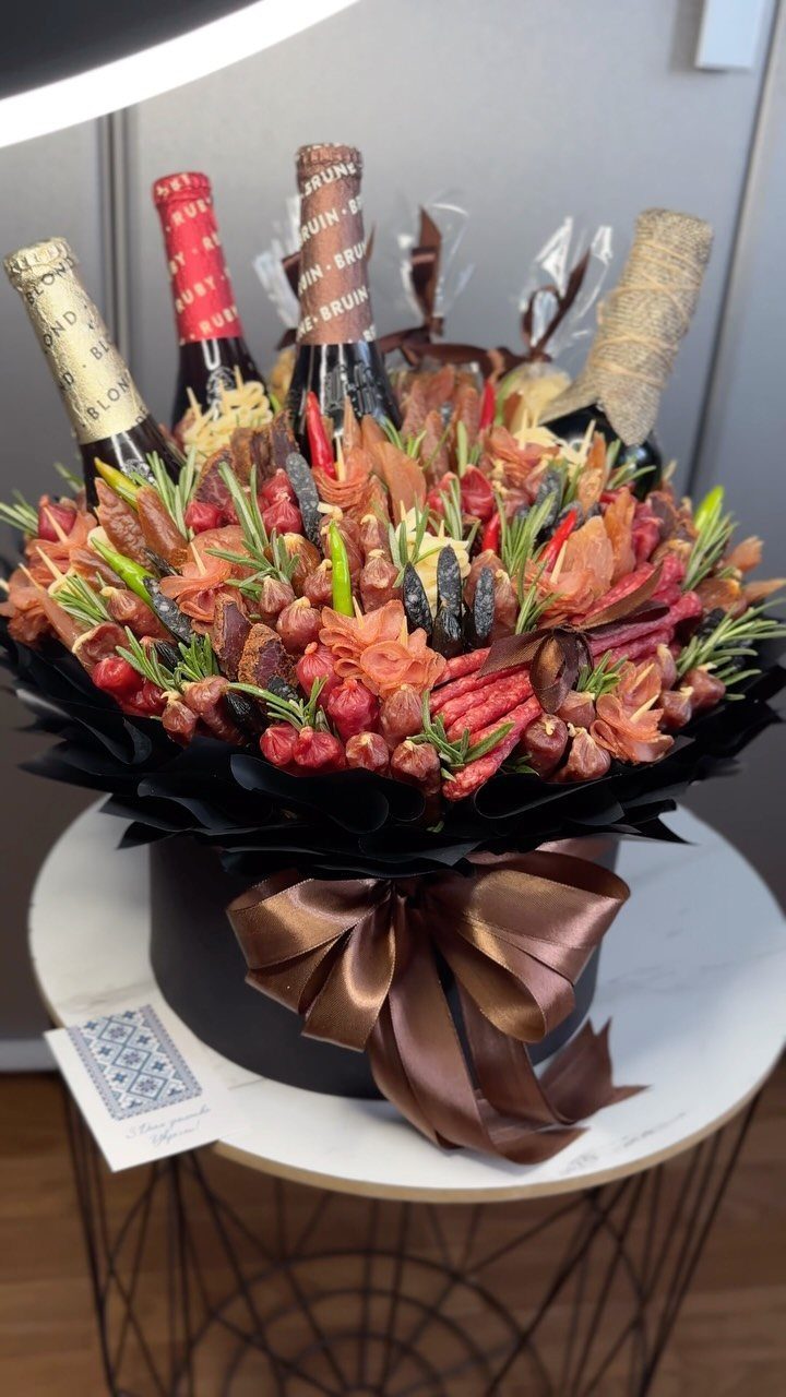 Meat and beverage bouquet in a black box with a brown ribbon.
