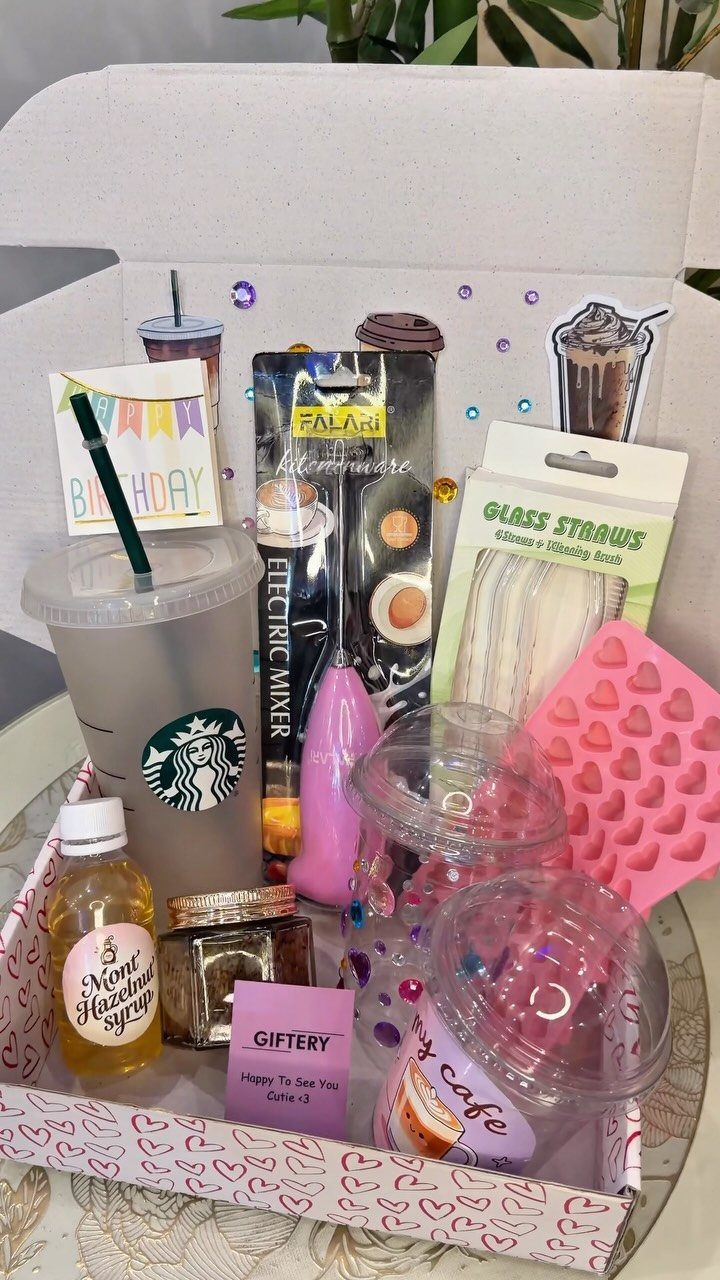 Coffee gift basket with Starbucks tumbler, pink frother, syrup, and heart-shaped accessories.