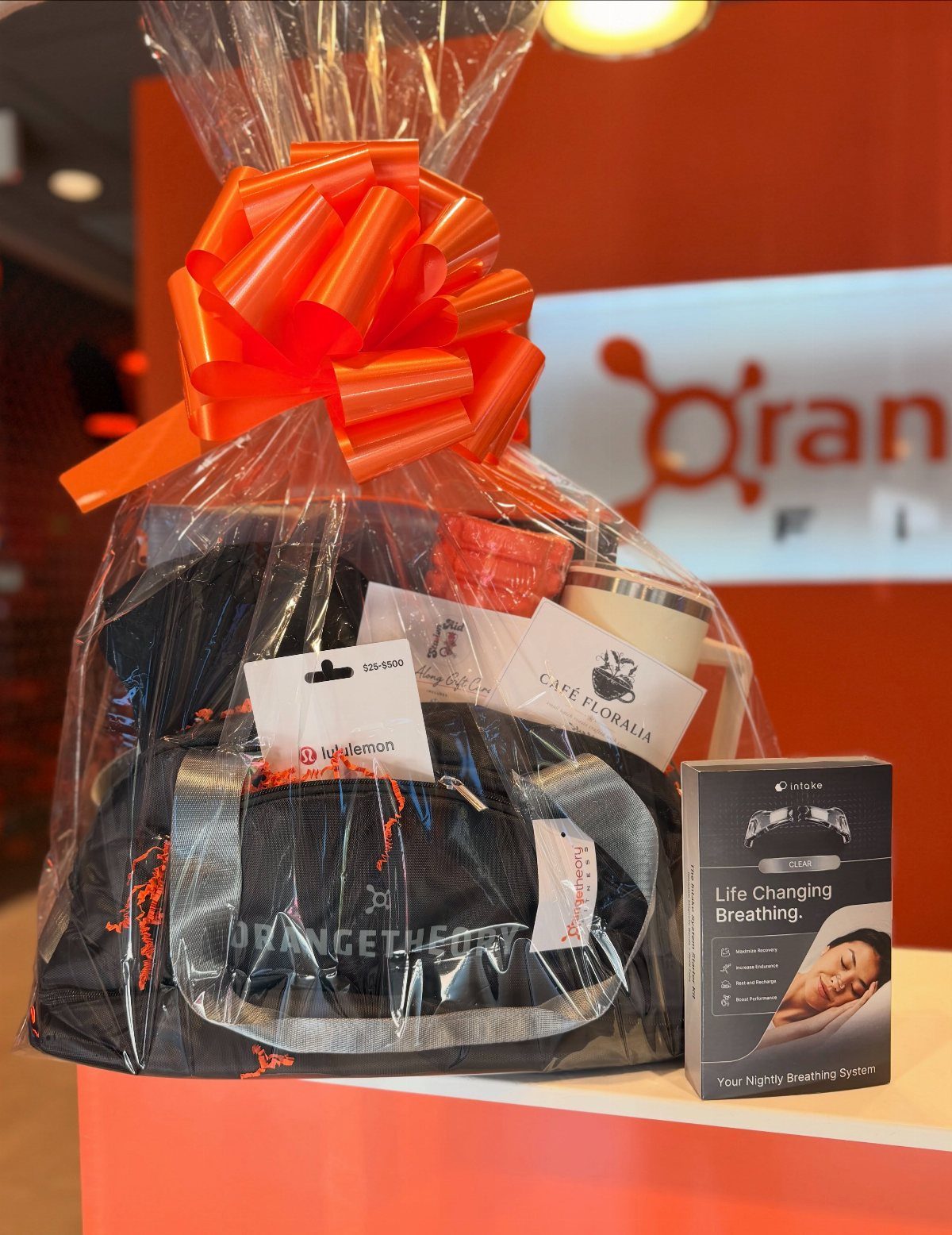 Gift basket with a black gym bag and orange bow for fitness enthusiasts.