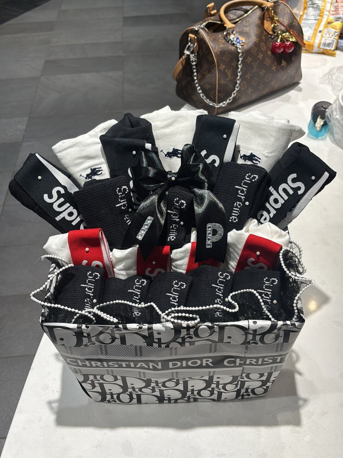 Designer gift basket filled with Supreme socks and white fabrics tied with ribbon.