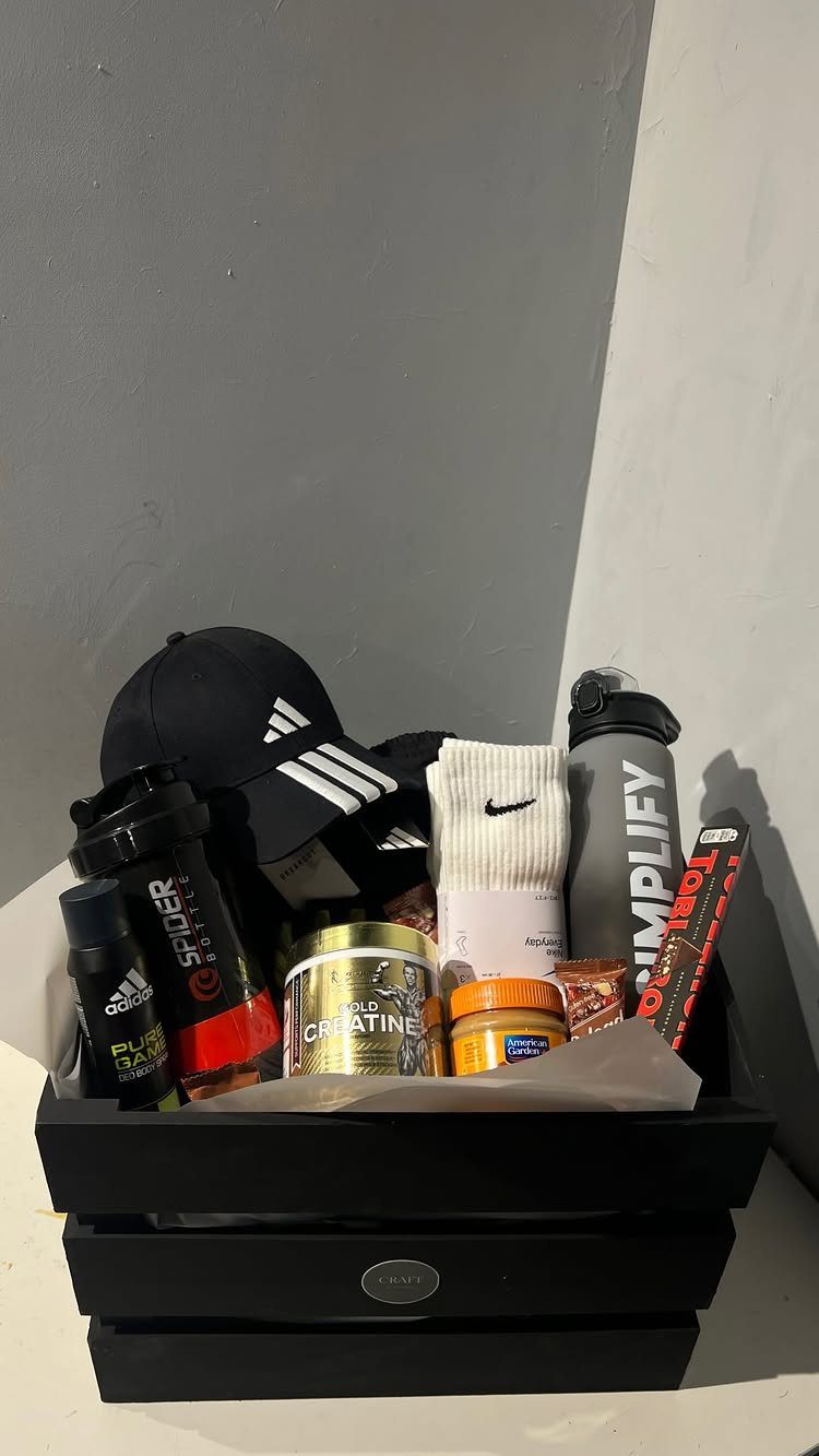 Fitness gift basket with black cap, white socks, water bottle, and supplements.