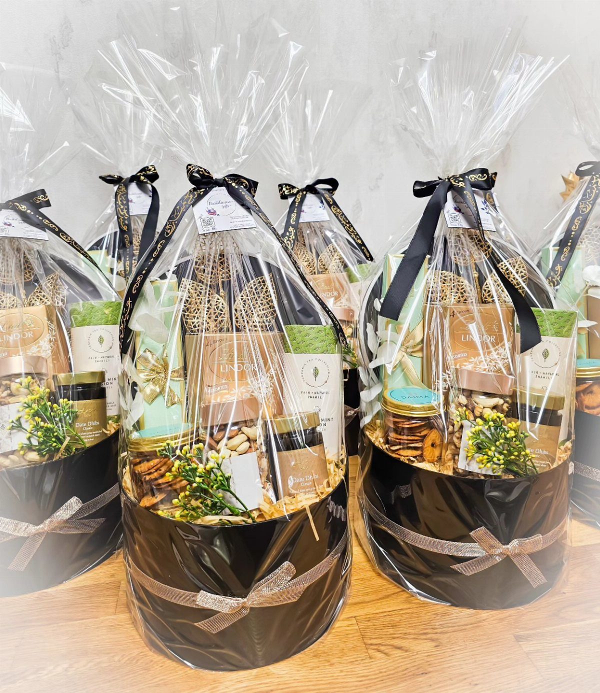 Round black gourmet food gift baskets wrapped in clear cellophane with black ribbons.