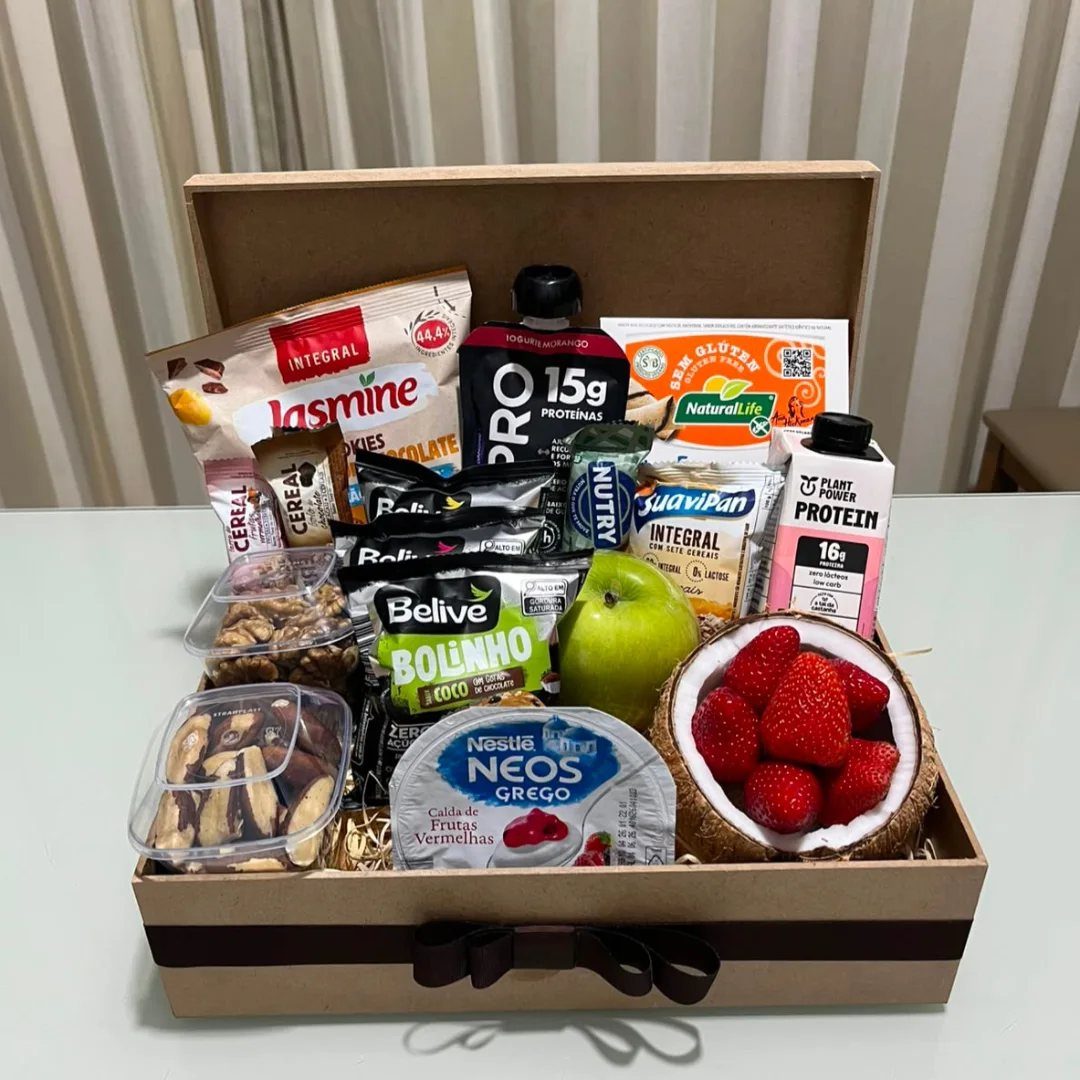 Healthy snack gift box with fresh fruit, nuts, and protein supplements in cardboard.