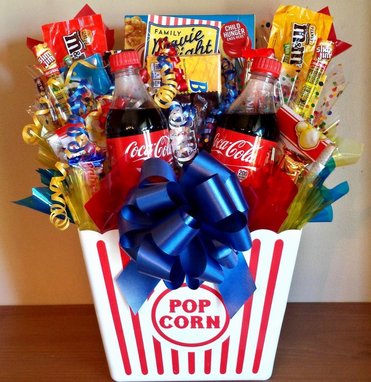 Popcorn bucket gift basket filled with soda, candy, and movie night signage.