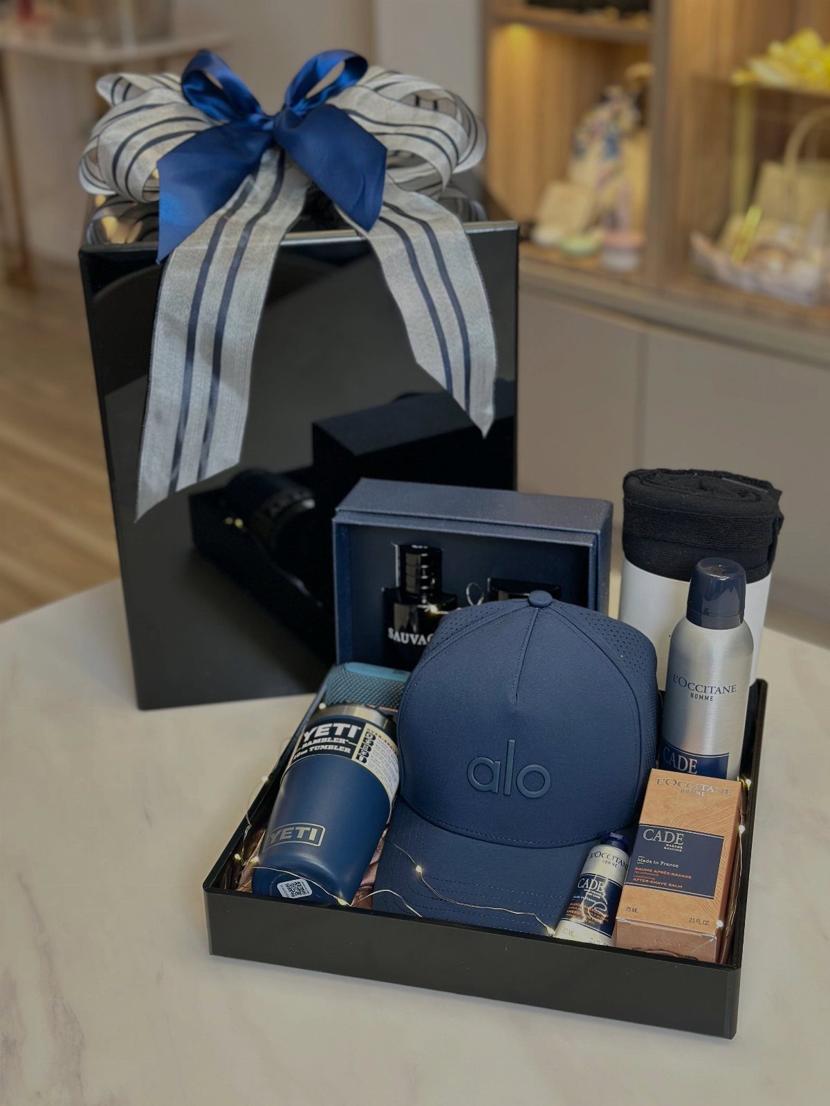 Blue baseball cap and Yeti tumbler in a black gift box with cologne.