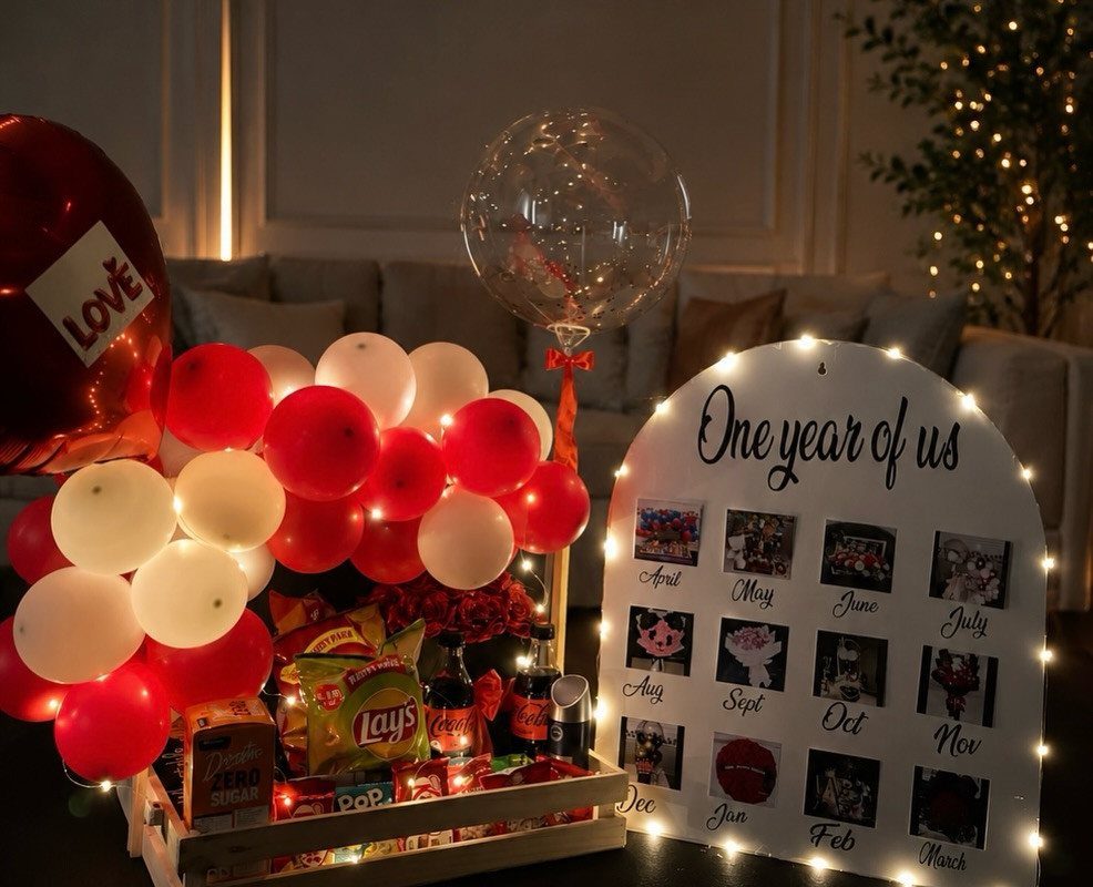 Romantic anniversary gift crate with red and white balloons and a photo board.