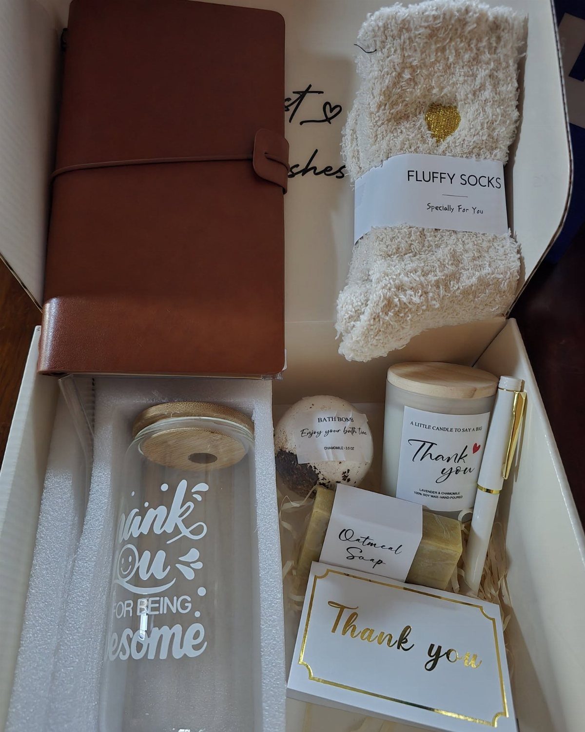 Gift box with leather notebook, fluffy socks, thank you card, and self-care items.