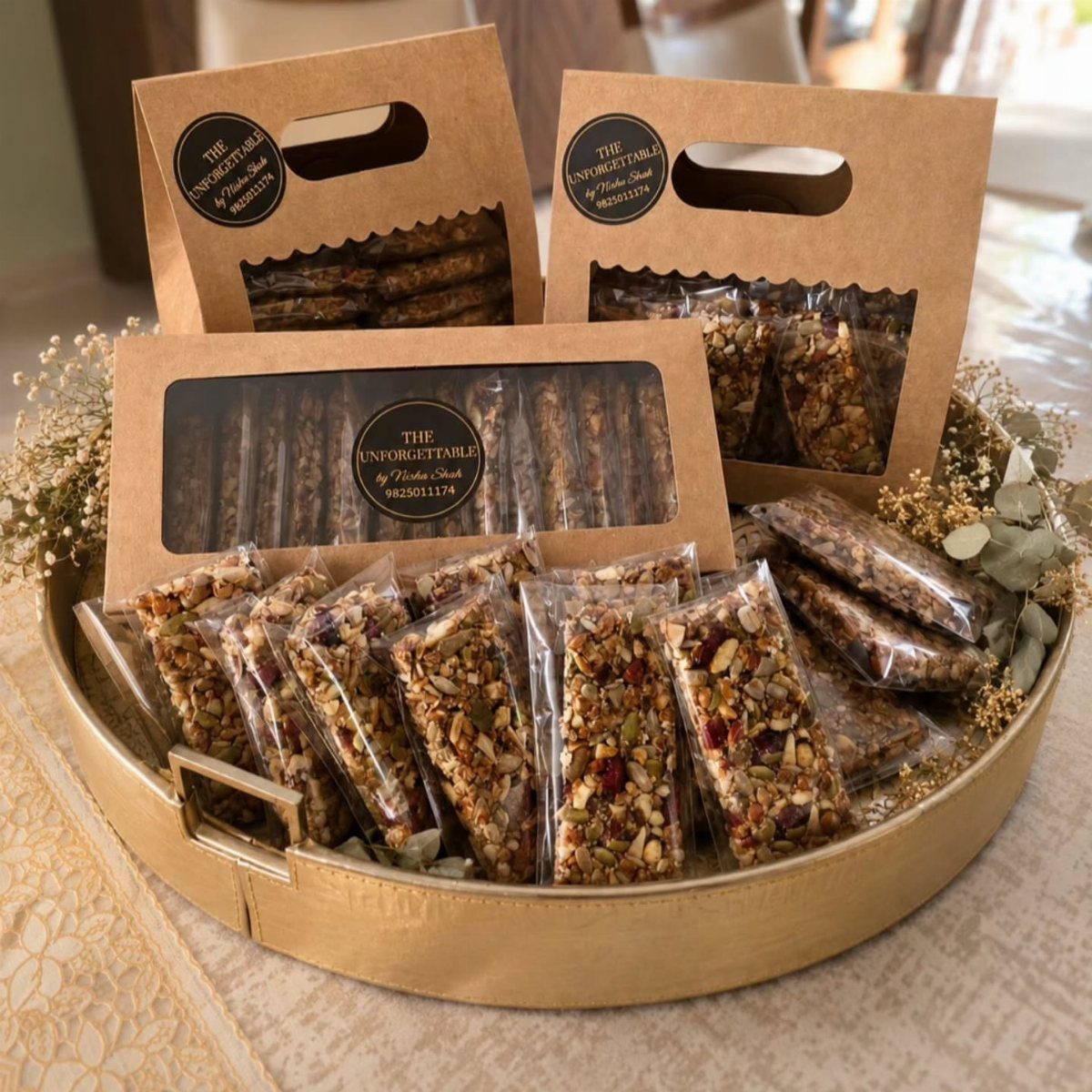 Granola bars in clear packaging and brown gift boxes arranged in a gold tray.