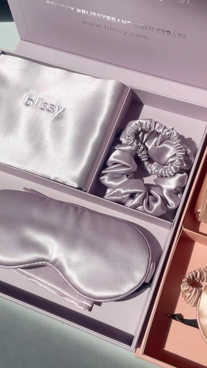 Satin sleep mask, scrunchie, and pillowcase in a light purple gift box.