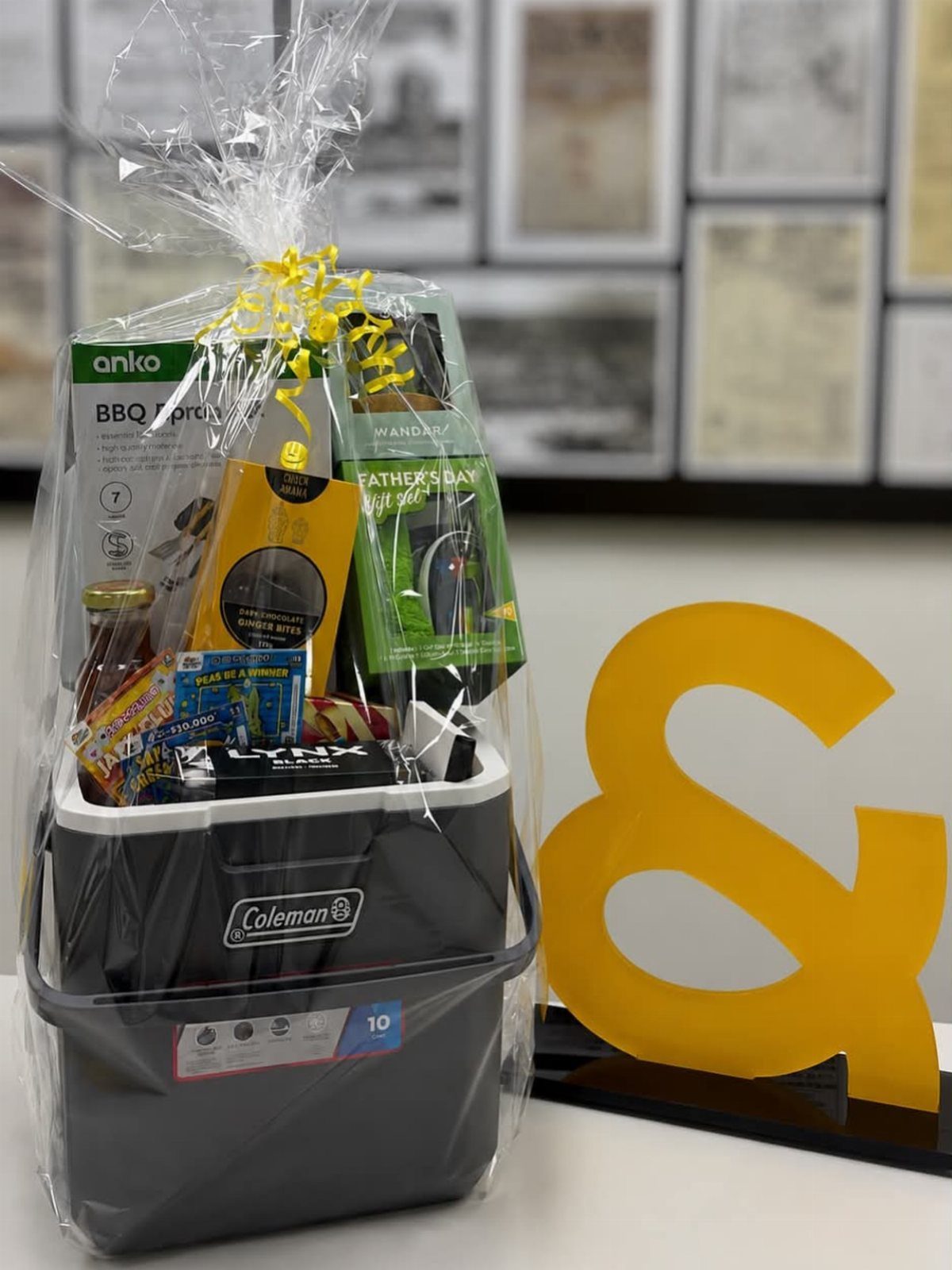 Gift basket in a grey cooler with BBQ tools and snacks wrapped in cellophane