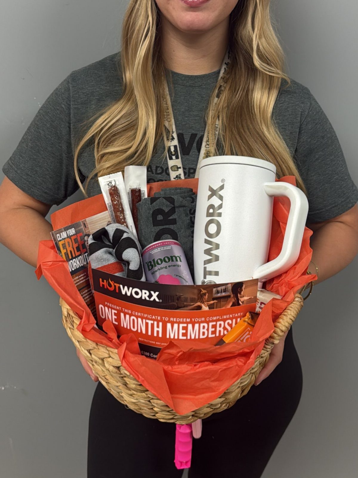Wicker gift basket containing fitness gear, a white mug, and a membership certificate.