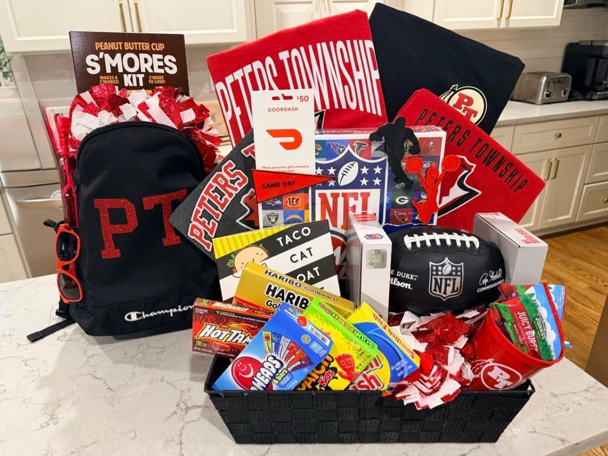 Sports-themed raffle basket with a black backpack, NFL football, and red towels.