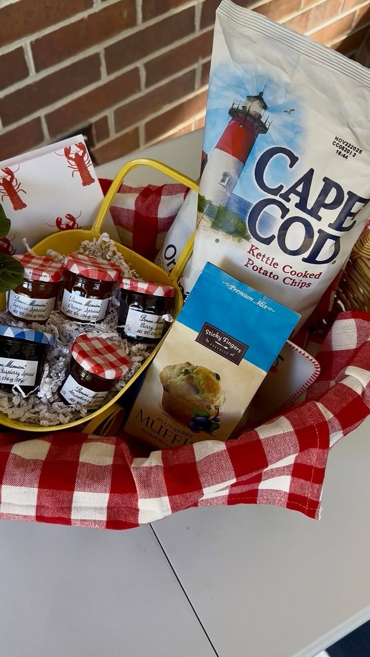 Yellow gift basket with potato chips, jam jars, and red checkered picnic cloth.