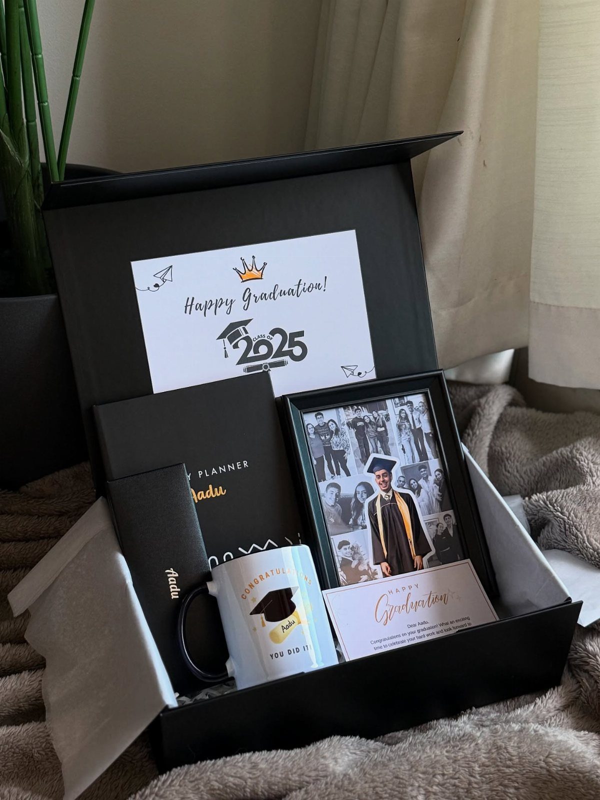 Graduation gift box with a framed photo, planner, mug, and celebratory cards.