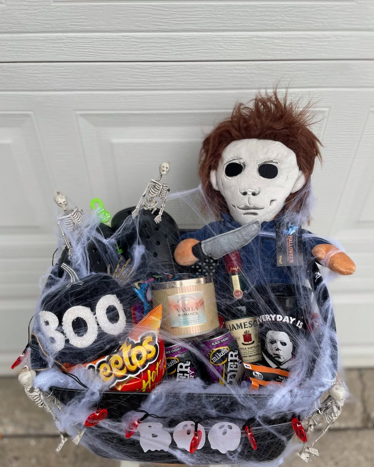 Halloween gift basket with Michael Myers doll, snacks, and spiderwebs on white background