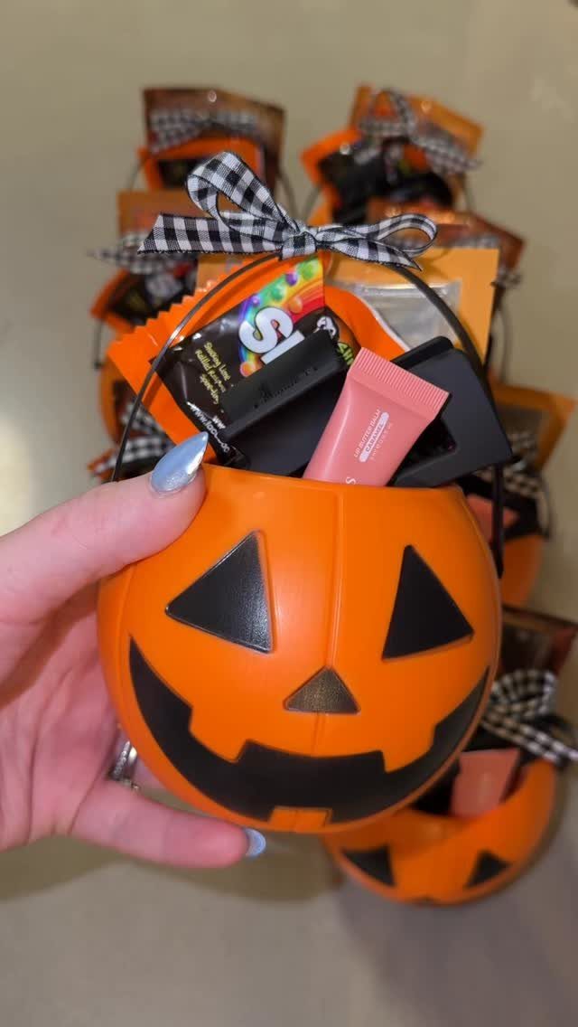 Orange pumpkin bucket filled with Halloween treats and tied with a checkered bow.