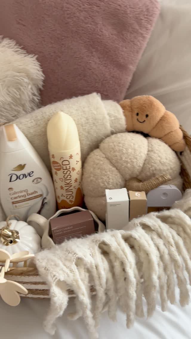 White woven basket filled with skincare, plushies, and a cozy knit blanket.