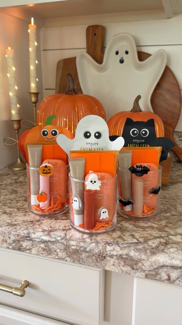 Three Halloween themed gift cups filled with skincare products and festive cardboard cutouts.