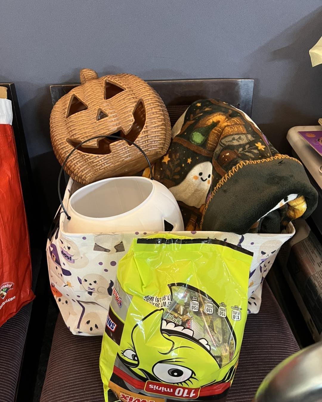 Halloween gift bag with a woven pumpkin, candy, and a patterned blanket.