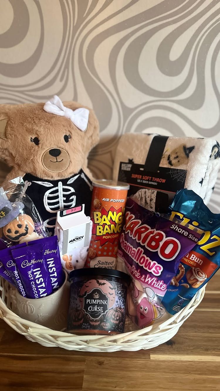 Halloween gift basket with skeleton teddy bear, candies, and a pumpkin candle.