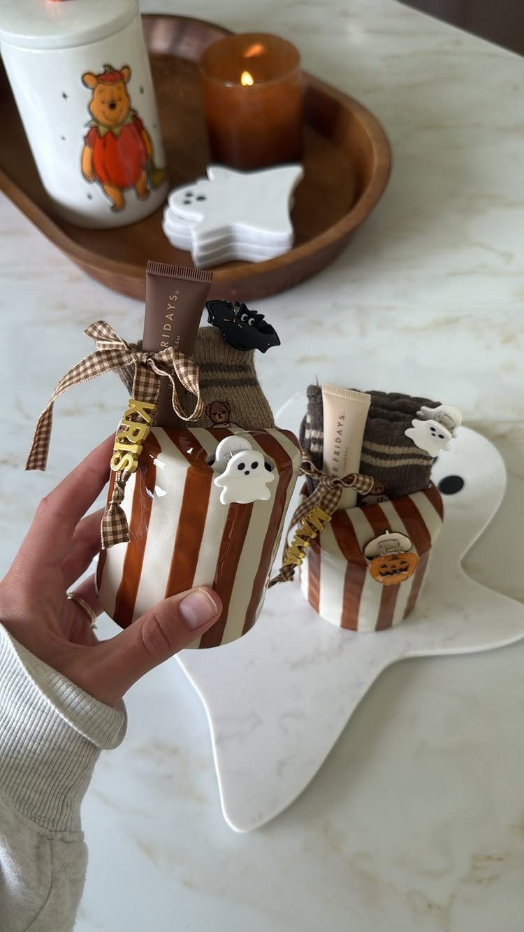 Small striped gift containers with Halloween treats on a ghost-shaped white tray.